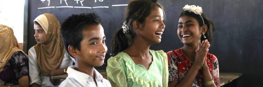 Glada pojkar och flickor i skolan framför svarta tavlan