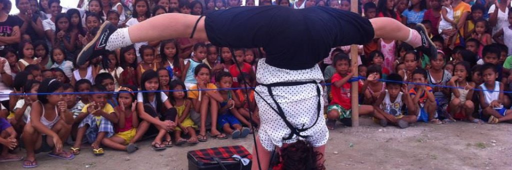 Clown står på händerna och gör en split inför en hänförd publik