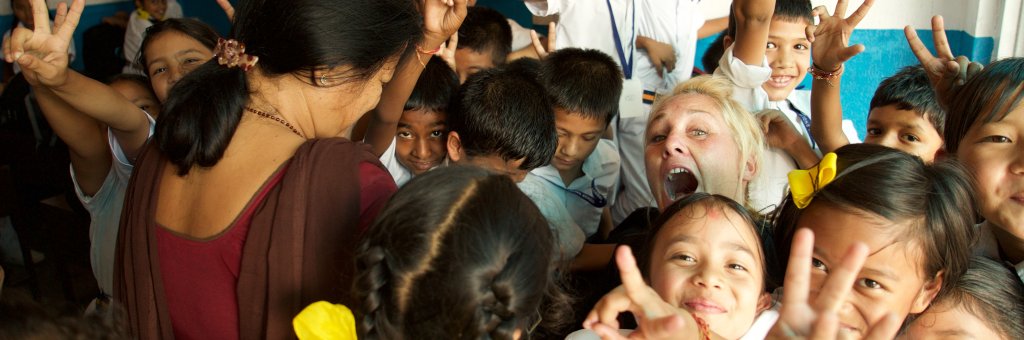 Clown omgiven av barn som ler och gör v-tecknet