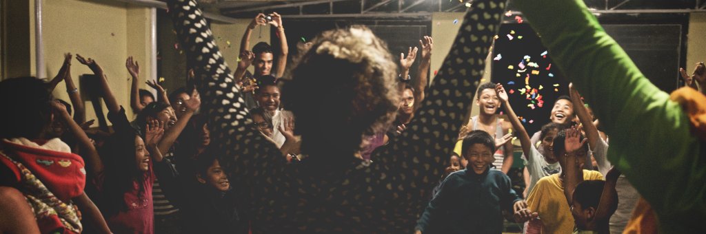 Två clowner sträcker upp armarna i luften inför en leende publik