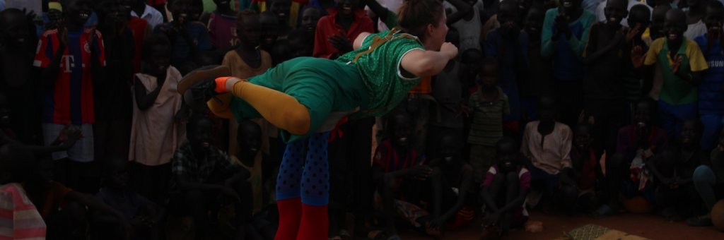 Två clowner utför ett akrobatiskt nummer inför en leende publik