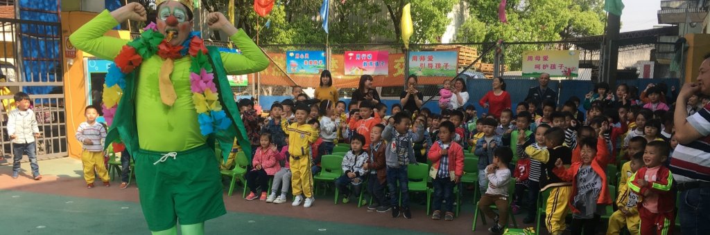 Clown i gröna kläder uppträder inför en publik av barn