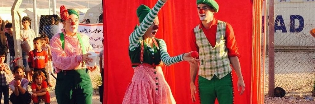 Tre clowner i färgglada kläder uppträder