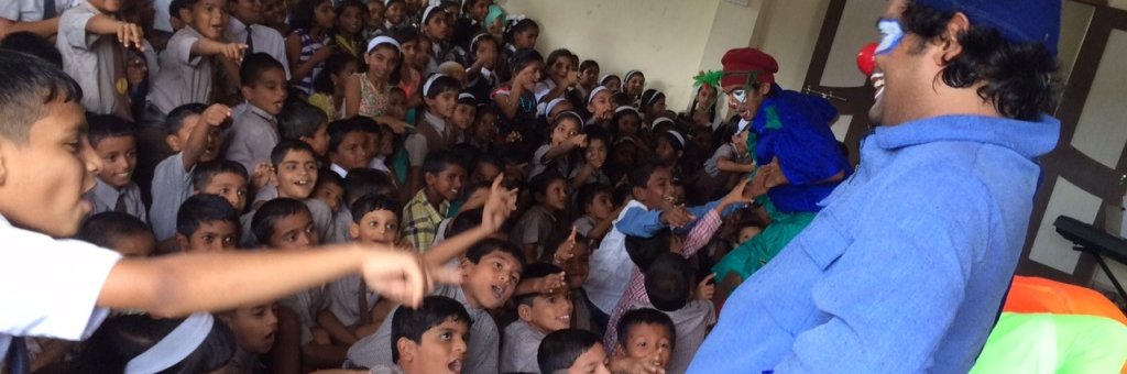 Leende clown på scen inför en stor publik av barn