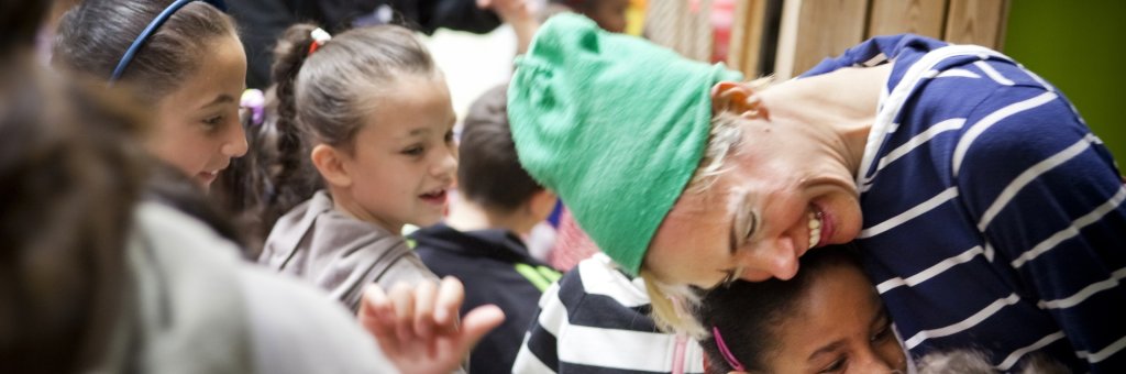 Leende clown omfamnar en flicka i publiken