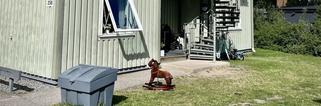 en liten gunghäst står på gräsmattan framför ett radhus