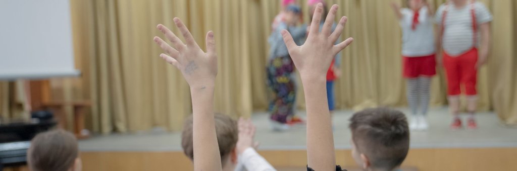 Två armar uppsträckta i luften, i förgrunden artister på scen