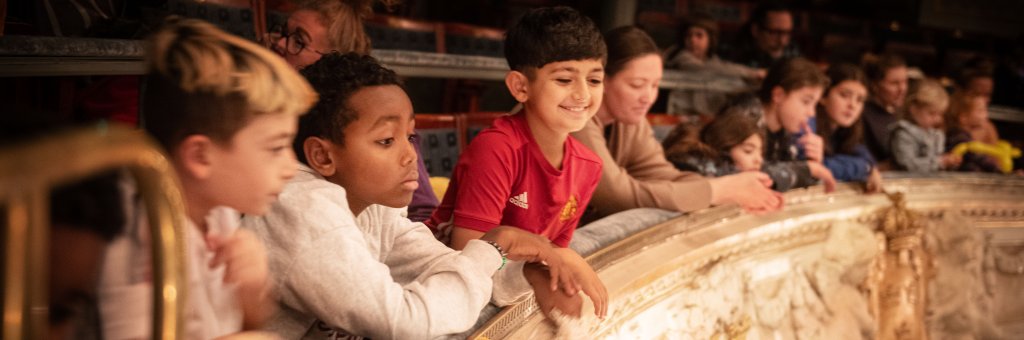 En grupp barn sitter på en balkong och ser på en föreställning