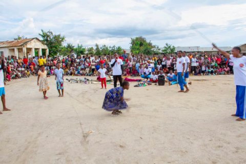 Barn hoppar hopprep medan artisterna vevar