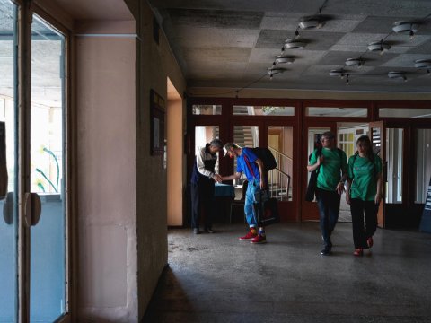 tre artister hälsar på en man i nedsläckta korridorer