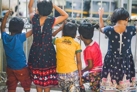 Barn i rad ser ut genom en järngrind