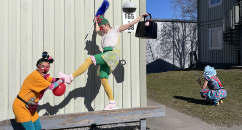 tre artister leker mellan gröna träbaracker