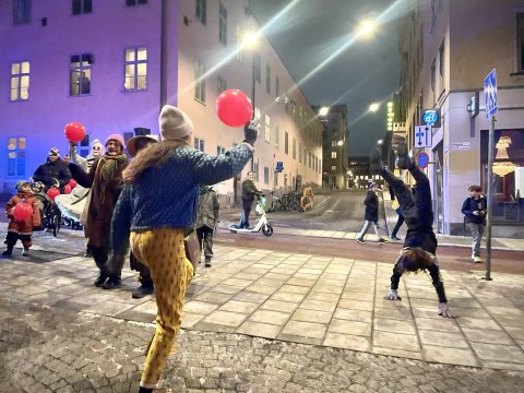 artster, vuxna och barn dansar och hjular på gatan med ballonger