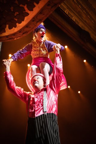 En clown som står på en annan clowns axlar