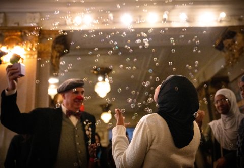 En clown som blåser såpbubblor och ett barn bakifrån i hijab