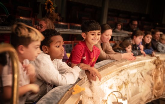 En grupp barn sitter på en balkong och ser på en föreställning