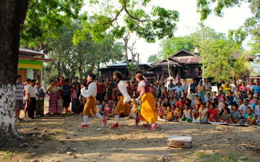 Clowner uppträder för publik i skydd av ett stort träd