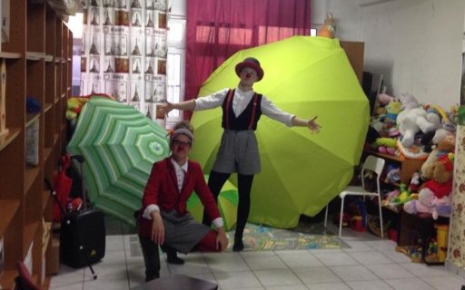 Två clowner poserar med gröna paraplyer i bakgrunden