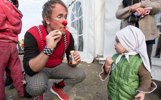 Clown blåser såpbubblor, ett litet barn tittar nyfiket på