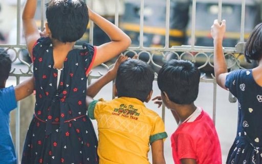 Barn tittar ut genom en gallergrind