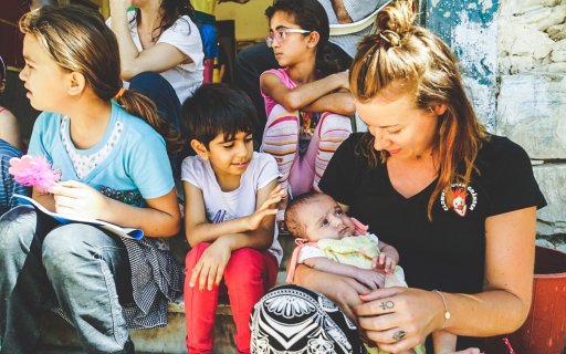 Kvinna sitter och håller ett barn i famnen omgiven av andra barn
