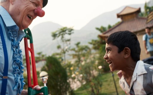 Clown med blåsinstrument och en skattande pojke