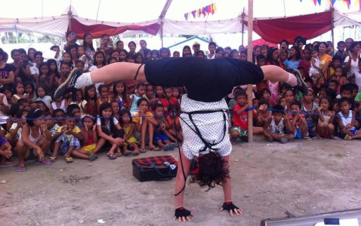 Clown står på händerna och gör en split inför en hänförd publik