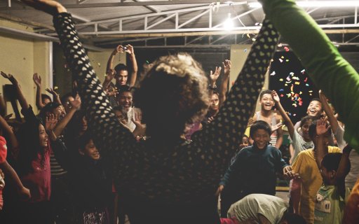 Två clowner sträcker upp armarna i luften inför en leende publik