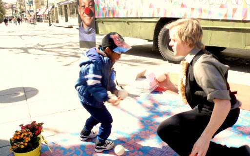 Clown leker med ett barn med tre vita bollar