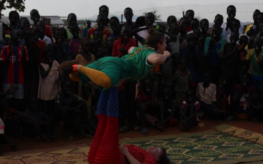 Två clowner utför ett akrobatiskt nummer inför en leende publik