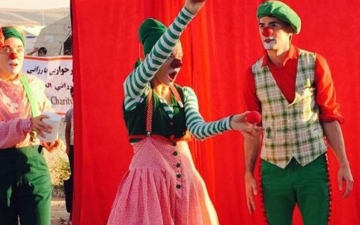 Tre clowner i färgglada kläder uppträder