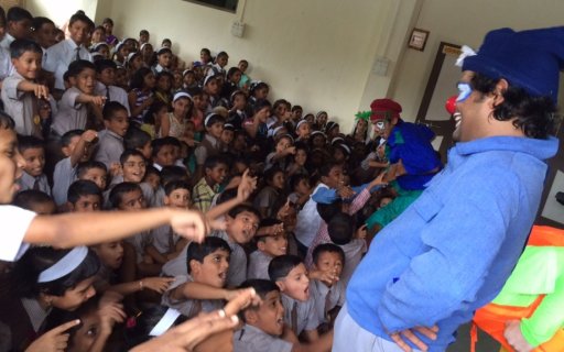 Leende clown på scen inför en stor publik av barn