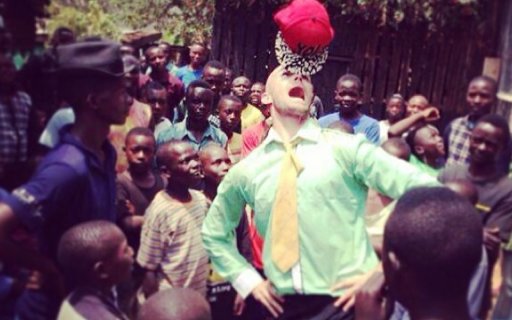 Clown balanserar ett på näsan omgiven av hänförd publik