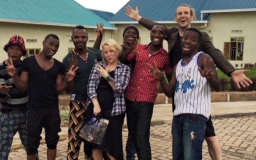 Artisterna poserar tillsammans framför en skola